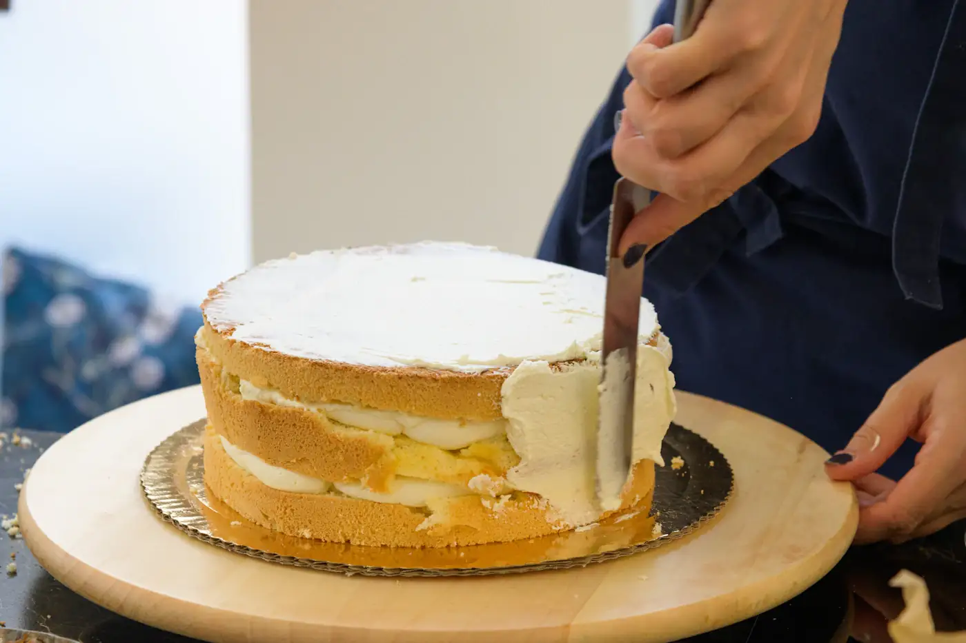 Cukrárka uhladzuje krém na plnenej piškótovej torte